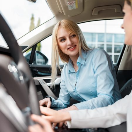 Elegant lady on a test drive with an instructor. Woman practiced to drive a car